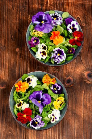 Seasonal pansy edible flower salad on a wooden table.