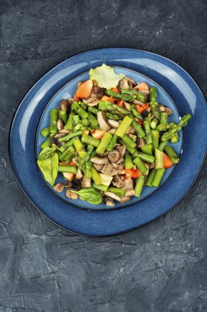 Téléchargez les photos : Salade de désintoxication aux légumes d'asperges vertes et de champignons frits dans une assiette. Une nourriture saine. Espace pour le texte. - en image libre de droit
