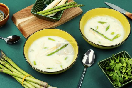 Veggie soup with white and green asparagus in bowl. Spring herb soup.