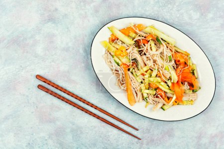 Salad with enoki mushrooms, carrots, cucumber and sesame seeds on a white plate. Menu for Chinese restaurant. Copy space for text.
