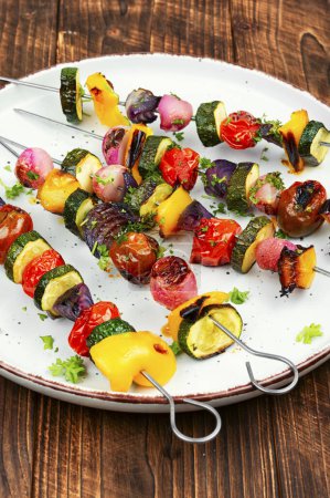 Grilled vegetable kebabs, skewers with vegetables on a wooden rustic table.