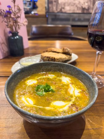 Soupe d'orge persane traditionnelle avec carotte et persil sur la table dans un café-lunch, offrant un aperçu alléchant du patrimoine culinaire au milieu de l'ambiance chaleureuse, avec vue sur le comptoir de service.