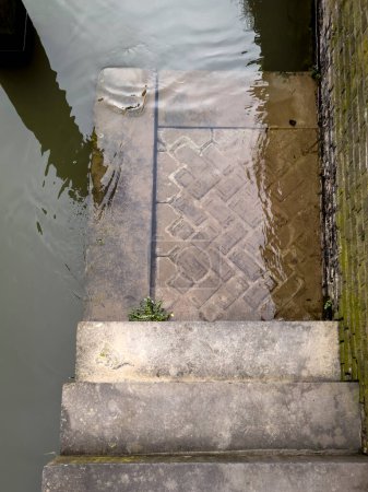 Steps leading down to the urban Dutch canal on a somber, rainy day, encapsulating the melancholic charm of urban landscapes in the Netherlands.