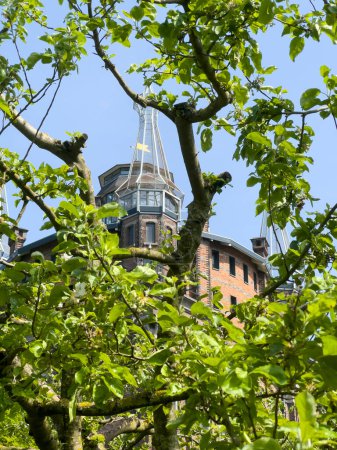 The tower of Villa Augustus Hotel emerges gracefully through the branches and lush leaves of the surrounding orchard, creating a picturesque scene of tranquillity and elegance in the garden.