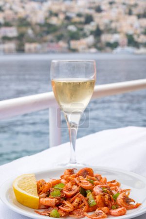 Photo for Plateful of Symi Shrimp Served ith a Slice of Lemon and a Glass of Greek White Wine - Royalty Free Image