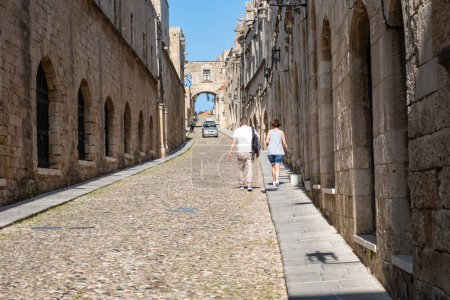 Foto de Rhodes Medieval City, Grecia - 19 de mayo de 2023: Una pareja de turistas caminando por la calle de los caballeros temprano en la mañana - Imagen libre de derechos