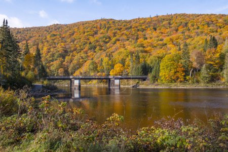 Foto de A Bridge Across the River Near Jacques-Cartier National Park 's Visitor' s Centre Rodeado de Fall Colors, Quebec, Canadá - Imagen libre de derechos