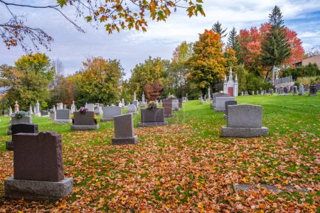 Téléchargez les photos : Cimetière catholique paisible avec pierres tombales en marbre et feuillage d'automne coloré comme toile de fond - en image libre de droit
