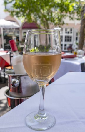 Ein Glas rosa Wein auf einem Tisch mit weißem Leinen im Patio eines Restaurants