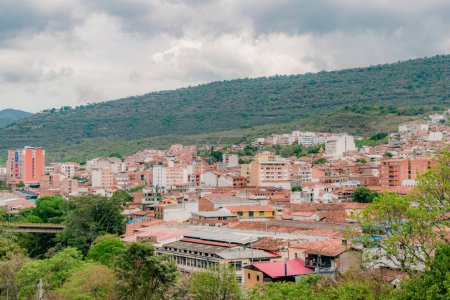 paisaje de la ciudad de San Gil, Santander, Colombia desde las montañas, con vegetación verde en primer plano que destaca el entorno verde de la ciudad