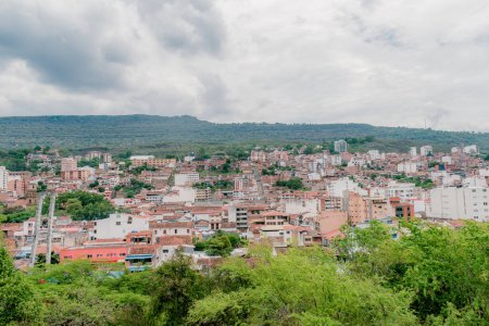 paisaje de la ciudad de San Gil, Santander, Colombia desde las montañas, con vegetación verde en primer plano que destaca el entorno verde de la ciudad