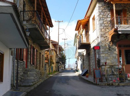 Téléchargez les photos : Une rue dans la ville d'architecture traditionnelle de Vytina à Arcadia, en Grèce. Le panneau dit gaufres, crêpes, baguettes, ouzo, tortillas - en image libre de droit