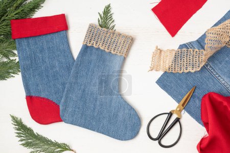 Téléchargez les photos : Projet de bricolage de bas de Noël en vieux jeans réutilisés. Facile décoration de Noël à la main, passe-temps, idée de cadeau durable. Concept upcycling. Couché plat, vue du dessus - en image libre de droit