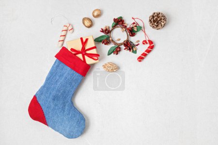 Photo for Red and blue denim Christmas stocking with gifts and decoration. Sustainble zero wastel Xmas celebration concept - Royalty Free Image
