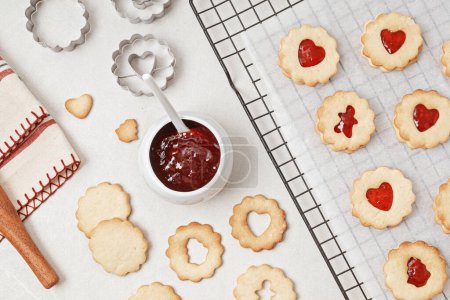 Photo for Baking traditional homemade Linzer or sandwich Christmas cookies filled with raspberry jam. Xmas baking idea - Royalty Free Image