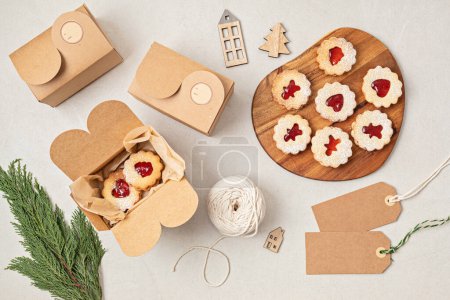 Foto de Galletas tradicionales Linzer o sándwich rellenas de mermelada de frambuesa envasadas en cajas de regalo. Paquetes de regalo hechos a mano de Navidad, pequeña empresa, idea de hornear en casa - Imagen libre de derechos