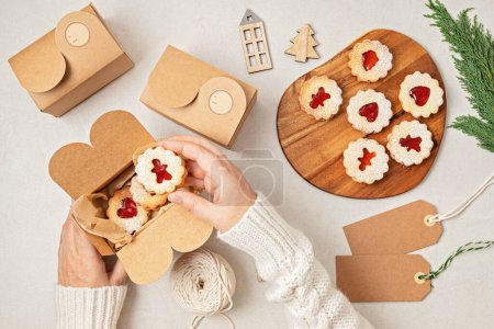 Téléchargez les photos : Biscuits traditionnels Linzer ou sandwich remplis de confiture de framboise emballés dans des boîtes-cadeaux. Emballages cadeaux faits main de Noël, petite entreprise, idée de cuisson à la maison - en image libre de droit