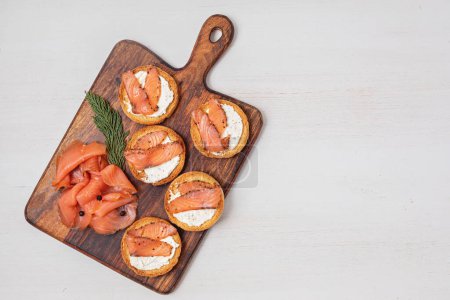 Foto de Aperitivos festivos con lonchas de salmón ahumado en tabla de cortar de madera - Imagen libre de derechos