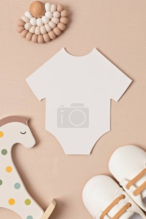 Photo for Baby shower, gender reveal party. Empty paper cut onesie. Flatlay, top view on a beige pastel background. Newborn gifts. Invitation, celebration, greeting card idea mockup - Royalty Free Image
