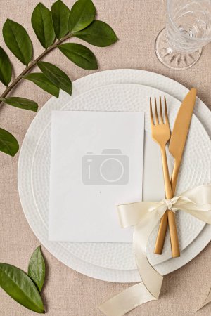 Téléchargez les photos : Festive wedding, birthday table setting with golden cutlery and porcelain plate. Blank card mockup. Party menu template. Flat lay, top view - en image libre de droit