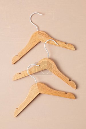 Photo for Wooden hangers on beige background. Responsible shopping, eco friendly home organization, sesonal sale concept. Top view, flat lay - Royalty Free Image