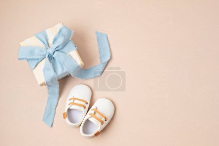 Téléchargez les photos : Baby shower, gender reveal, birthday party background with gift box and baby shoes. Top view, flatlay, copy space - en image libre de droit