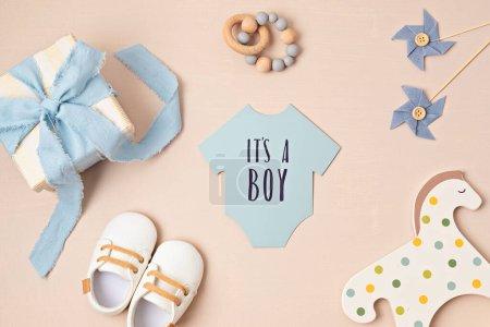 Photo for Baby shower, gender reveal party. It's a boy message over paper cut onesie. Flatlay, top view. Newborn gifts. Invitation, - Royalty Free Image
