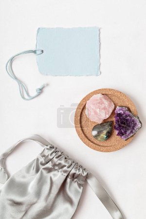 Téléchargez les photos : Kit cristaux pour le calme et la relaxation. Améthyste, quartz rosé, pierres précieuses de labradorite pour guérir l'anxiété et la santé mentale idée cadeau. Couché plat, vue du dessus avec tag mockup - en image libre de droit