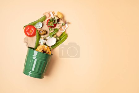 Photo for Green compost bin and kitchen leftovers. Recycling scarps, sustainable and zero waste lifestyle concept. Fruits and vegetable garbage waste turning into organic fertilizerd soil. Top view, flatlay - Royalty Free Image