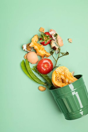 Green compost bin and kitchen leftovers. Recycling scarps, sustainable and zero waste lifestyle concept. Fruits and vegetable garbage waste turning into organic fertilizerd soil. Top view, flatlay