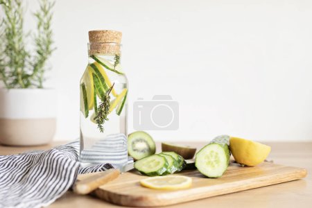Photo for Infused  water with cucumber, lemon and thyme in glass bottle on wooden table. Diet, detox, healthy eating, weight loss concept - Royalty Free Image