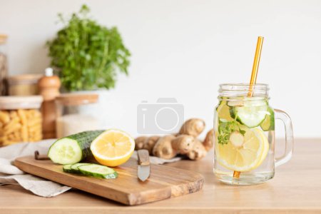 Téléchargez les photos : Eau infusée de concombre, citron et gingembre en bouteille de verre sur table en bois. Régime alimentaire, désintoxication, saine alimentation, concept de perte de poids - en image libre de droit