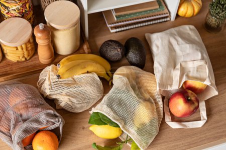 Foto de Frutas en bolsas reutilizables en la mesa de la cocina. Sostenible, cero residuos, estilo de vida saludable, desintoxicación ambiental personal. - Imagen libre de derechos