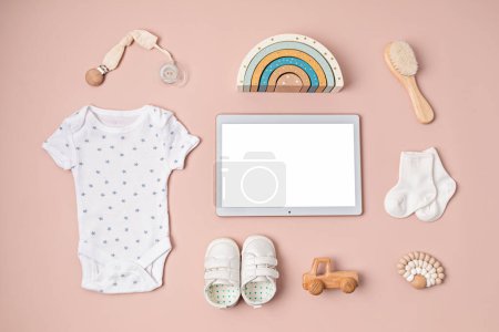 Photo for Mockup of infant bodysuit made of organic cotton with eco friendly baby accessories and touchpad with white screen. Template for online branding, shop, advertising. Flat lay, top view - Royalty Free Image