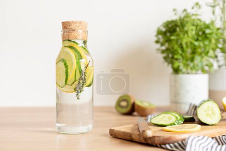 Foto de Agua infundida con pepino, limón y tomillo en botella de vidrio sobre mesa de madera. Dieta, desintoxicación, alimentación saludable, concepto de pérdida de peso - Imagen libre de derechos