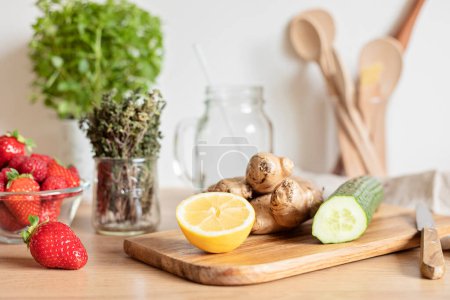Photo for Preparation of infused water with cucumber, lemon and ginger in glass jar on wooden table. Diet, detox, healthy eating, weight loss concept - Royalty Free Image