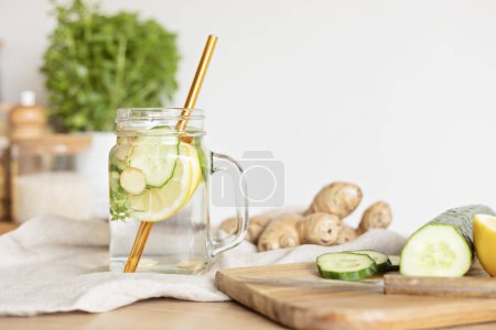 Photo for Infused  water with cucumber, lemon and ginger in glass bottle on wooden table. Diet, detox, healthy eating, weight loss concept - Royalty Free Image