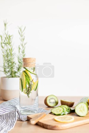 Foto de Agua infundida con pepino, limón y tomillo en botella de vidrio sobre mesa de madera. Dieta, desintoxicación, alimentación saludable, concepto de pérdida de peso - Imagen libre de derechos