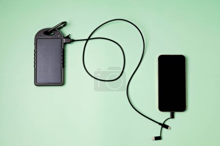 Téléchargez les photos : Chargeur de batterie solaire pour appareils mobiles. Concept de mode de vie durable et d'énergies renouvelables vertes - en image libre de droit