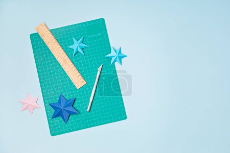 Photo for Top view over paper  cut tools, scissors, cutter, cutting mat, and crafted paper objects. DIY trendy project concept. Flat lay - Royalty Free Image