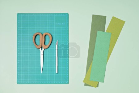 Photo for Top view over paper  cut tools, scissors, cutter, cutting mat, and crafted paper objects. Creative hobby, DIY trendy project concept. Flat lay - Royalty Free Image