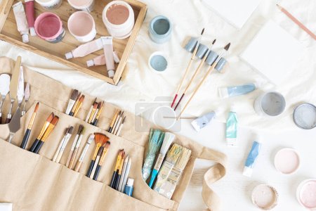 Téléchargez les photos : Ceinture de peintre pour artistes avec pinceaux, outils et couleurs. Artisanat hobby arrière-plan. Reconfortant, passe-temps déstressant, art thérapie - en image libre de droit