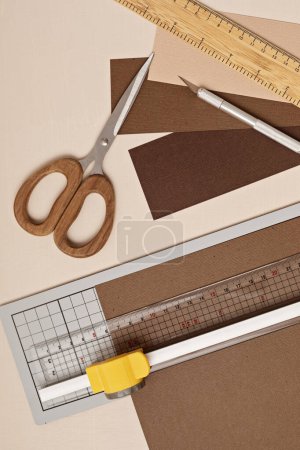 Photo for Top view over paper cut tools, scissors, cutter, cutting mat, and crafted paper objects. DIY trendy project concept. Flat lay - Royalty Free Image