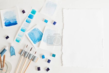 Foto de Artista pintando paletas de acuarela en pastel azul con pinceles. Antecedentes artísticos. Recomfortar, destronar hobby, arte - Imagen libre de derechos