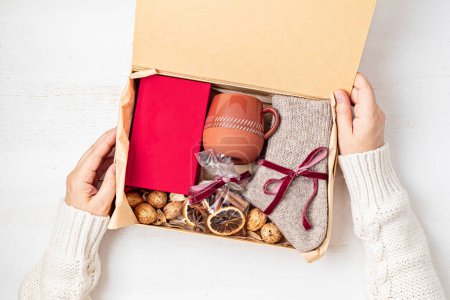 Photo for Preparing care package with warm socks, book, coffee cup, aroma spices. Personalized eco friendly basket for fall, winter holidays, christmas, wishig recovery to family, friend. Get well soon gift box - Royalty Free Image
