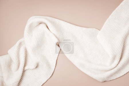 Téléchargez les photos : Foulard en laine beige sur fond pastel. Des vêtements élégants pour femme. Accessoires de mode hiver - en image libre de droit