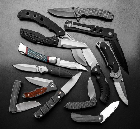 Beaucoup de couteaux de poche. Une variété de couteaux pliants sur un fond métallique gris.