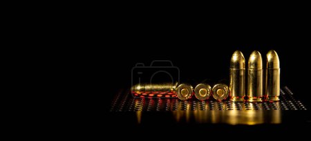 Cartuchos de pistola de 9 mm sobre una superficie lisa y brillante con reflejos. Munición para pistolas y carabinas PCC sobre fondo oscuro.