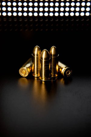 Cartuchos de pistola de 9 mm sobre una superficie lisa y brillante con reflejos. Munición para pistolas y carabinas PCC sobre fondo oscuro.