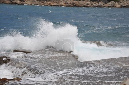 Foto de La ola del mar chocando contra la roca y hacer que el agua salpicando y burbuja de espuma de aire blanco. Rompiendo olas en la playa.Rompiendo olas marinas en la costa rocosa - Imagen libre de derechos
